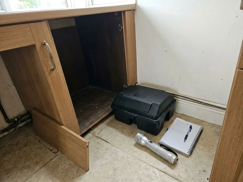 Rat bait station placed discreetly behind a kitchen cabinet